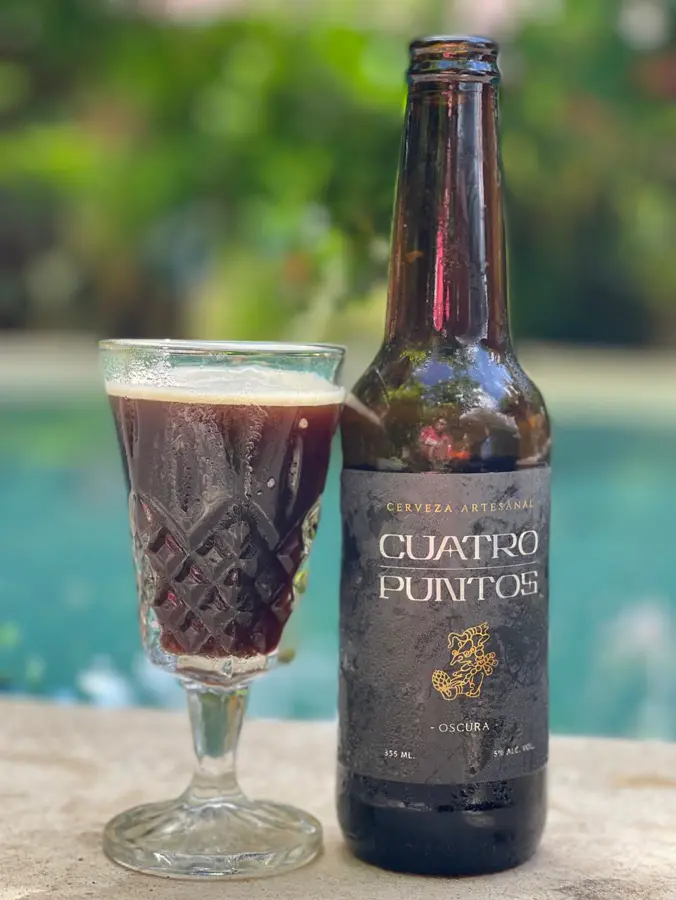 Cuatro Puntos Oscura servida en copa junto al agua