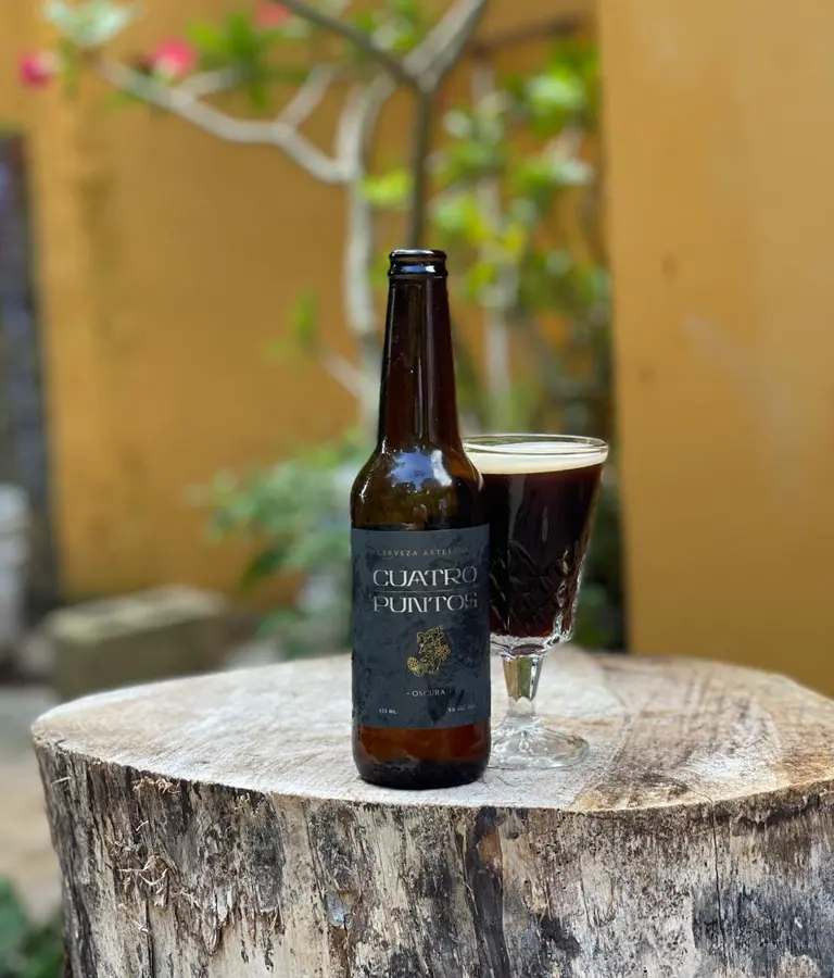 Botella y copa Cuatro Puntos sobre un tronco